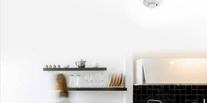 Eine minimalistische Küche mit weißen Wänden und schwarz gefliester Rückwand, mit offenen Regalen, in denen Tassen, Becher und eine Teekanne ordentlich angeordnet sind.